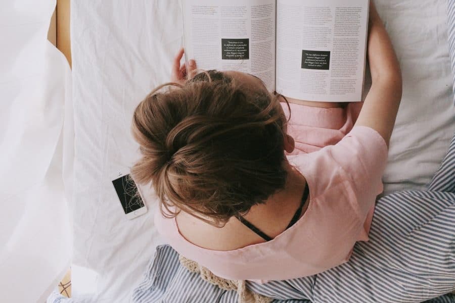 woman in pink dress sitting on bed while reading 698158 900x600 - 5 ways to relax and reconnect with yourself during quarantine