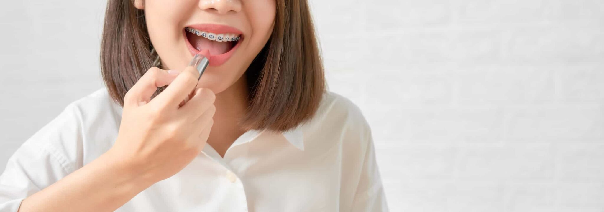 close up asian woman gorgeous charming holding pink lipstick with touch mouth scaled - 12 Things to Know About Braces or Invisalign